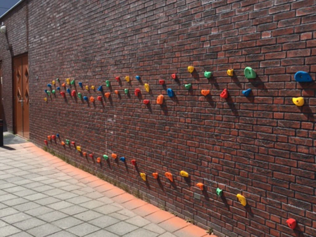 klimgrepen tegen basksteen muur schoolplein.webp