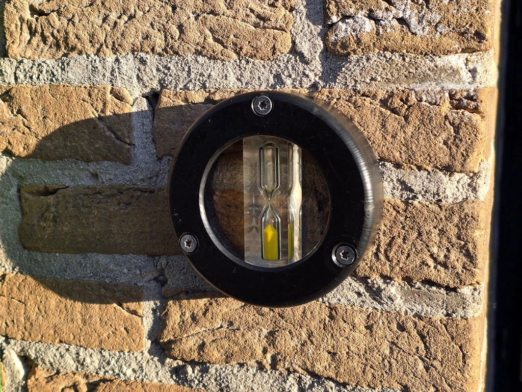 beurtrol zandloper op baksteen muur.webp